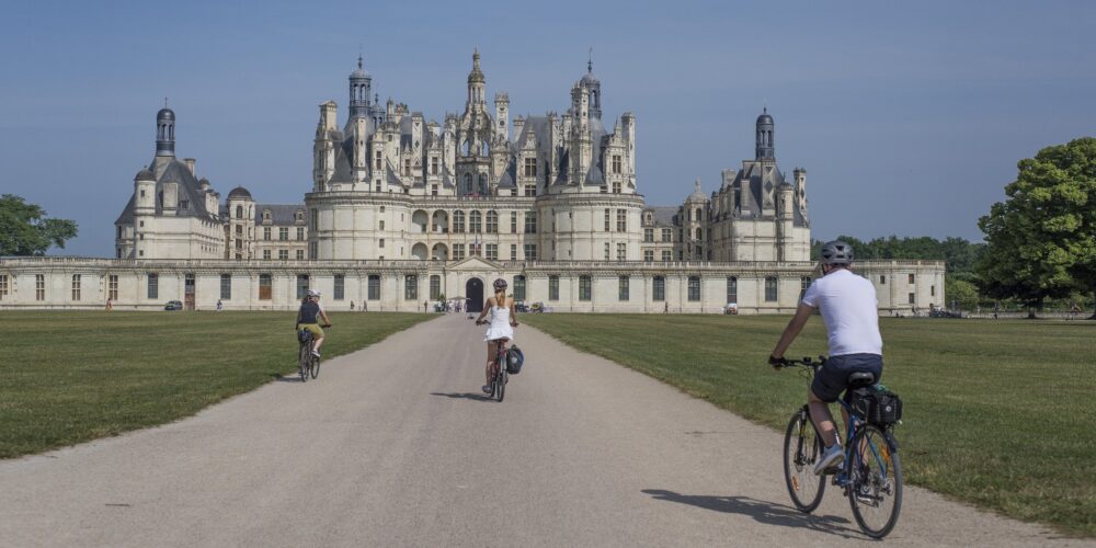 Rowerzyści w alei prowadzącej do zamku Chambord